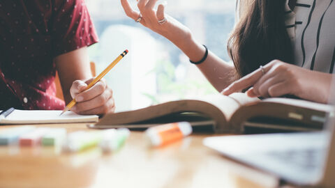 Eine Lerngruppe im Gespräch; auf dem Tisch liegen Bücher und Skripte