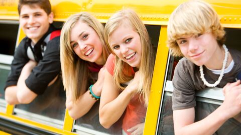 Austauschfahrten  Eine Gruppe von Jugendlichen, die aus den Fenstern eines gelben Busses schauen