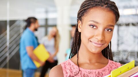 Berufliche Erstausbildung  Eine junge Auszubildende mit Unterlagen unterm Arm