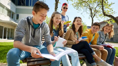 Partnerschulen  Schüler vor einer Schule, die miteinander reden und Spaß haben