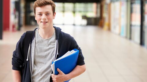 Eine andere Schule als die zuständige besuchen Ein junger Mann mit Aktenordner unter dem Arm auf einem Schulflur