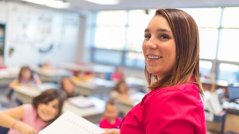 Eine Lehrerin im Klassenzimmer, die den Betrachter direkt anblickt
