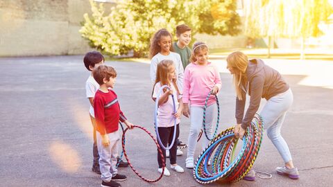 Eine Gruppe Schulkinder auf dem Schulhof mit Hula-Reifen