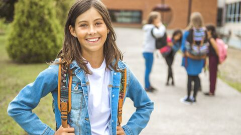 Bosnisch Ein Mädchen in Jeansjacke vor einem Schulgebäude