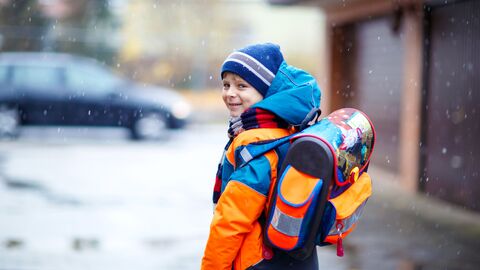 Schulbildungskosten Ein Schüler mit Jacke und Ranzen auf dem Weg zur SChule