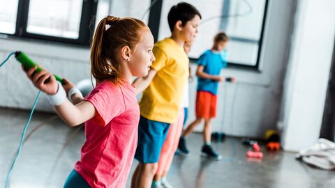 Gesundheitsförderung an Schulen Kinder, die im Sportunterricht Seil hüpfen