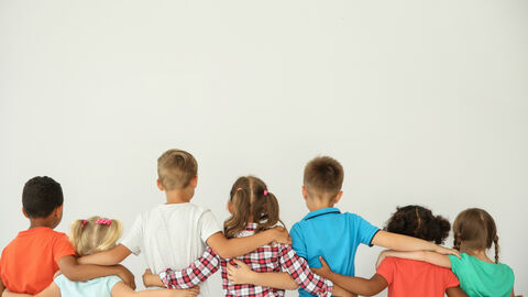 Eine Reihe Kinder von hinten, die ihre Arme umeinander legen