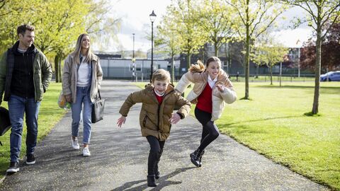 Mitbestimmung der Eltern Eltern mit zwei Kindern vor einer Schule