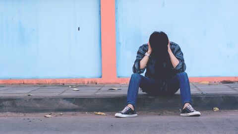 Ein Jugendlicher sitzt nachdenklich am Straßenrand