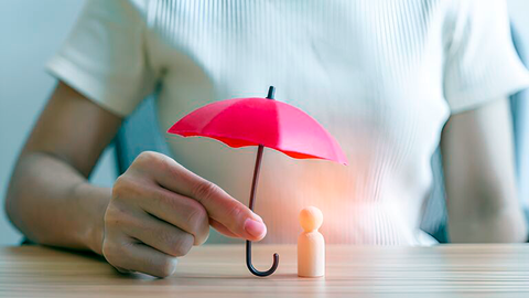 Ein Schirm wird über eine kleine Holzfigur gehalten