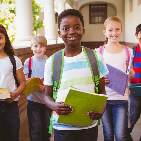 Unterricht in der Herkunftssprache Kinder unterschiedlicher Herkunft und Nationen, die nebeneinander auf einem Schulflur stehen und den Betrachter anschauen